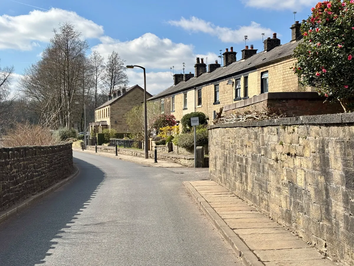 Stone terraced houses behind a garden wall on Hamer Terrace in Summerseat