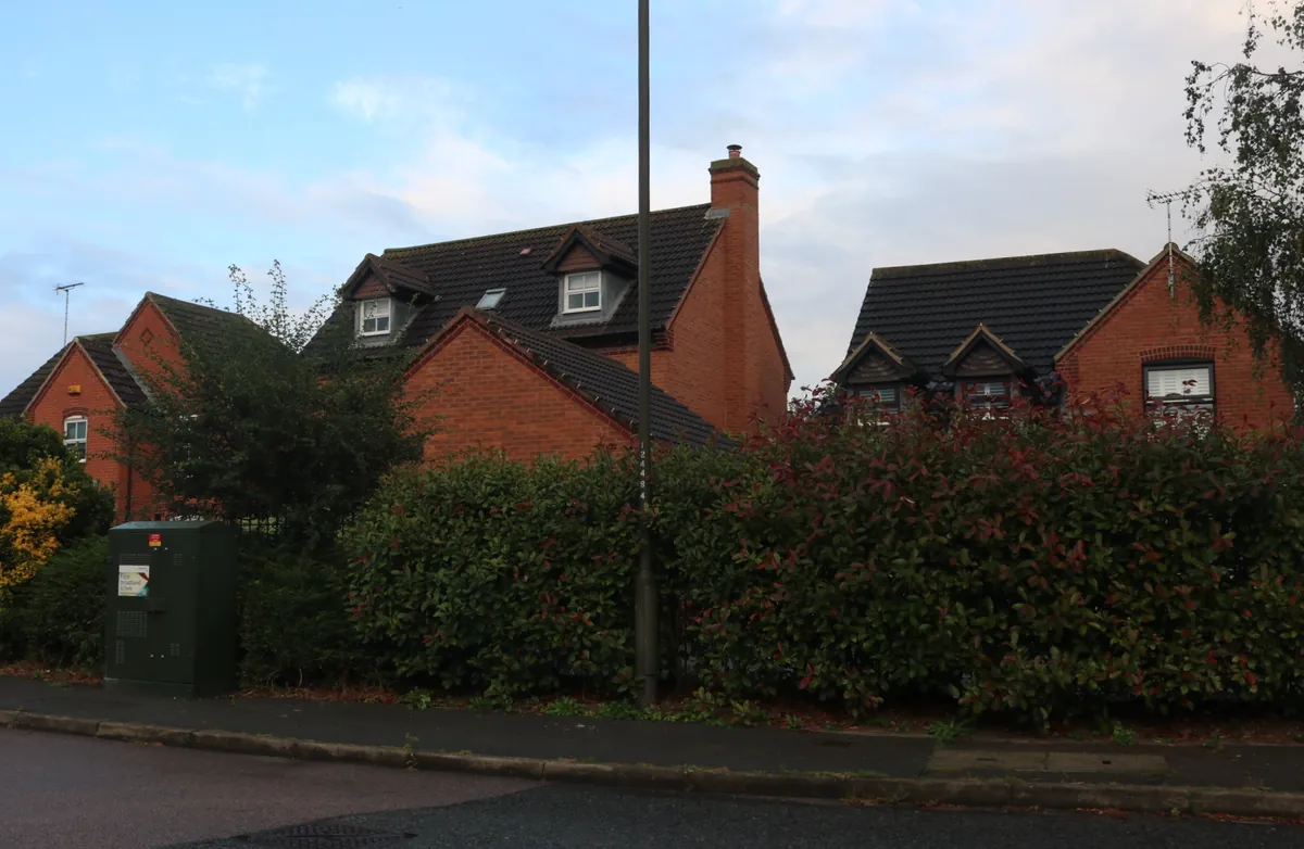 Modern red-brick detached houses with dormer windows behind a hedge on Avon Way in Hilton