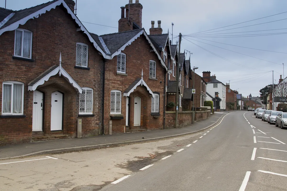 A row of red-brick cottages with white gabled porches along Main Street in Repton