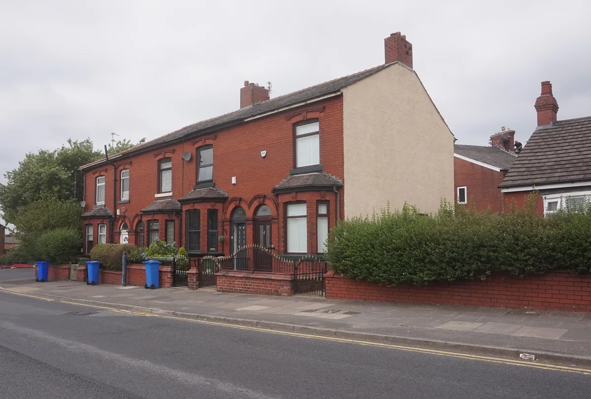 Red-brick terraced houses with bay windows on Mossley Road, Ashton-under-Lyne